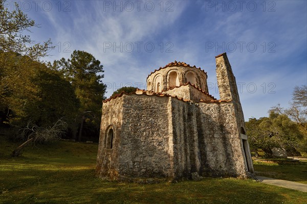 Historic church with stone façade in a rural landscape under a blue sky, Byzantine chapel Agios