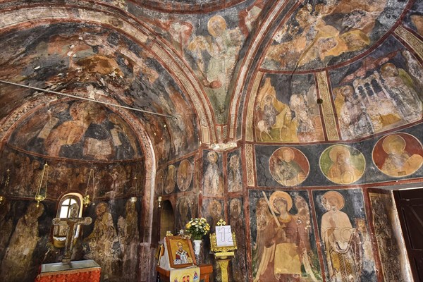 A church interior with dark frescoes on the walls, decorated with religious art and altars,