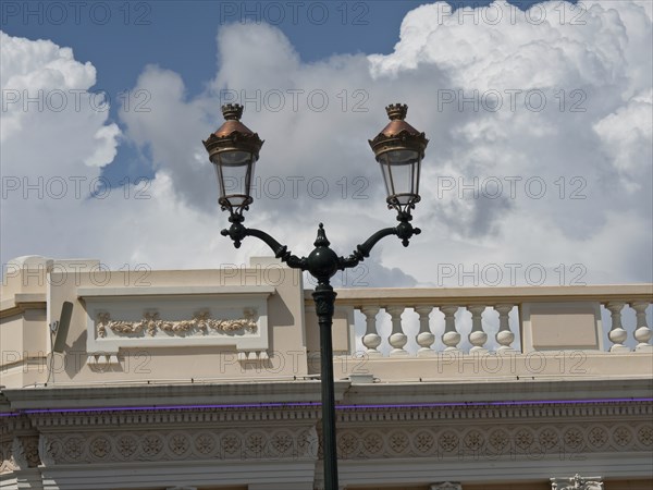 Historic street lamp in front of an old building with a sky full of clouds in the background,