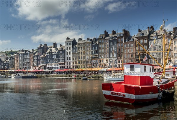 Red boat in front of the pitiresque buildings in Honfleur, Normandy