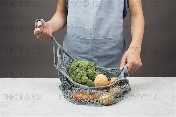 Mesh bag with vegetables, shopping grocery, healthy food ingredients, potato, broccoli and carrots,