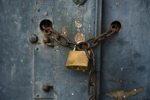 Old weathered door locked with a padlock and a rusty chain