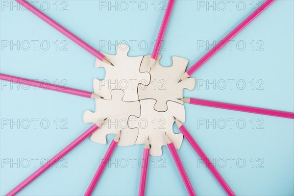 Working as a team, puzzle pieces connect together, pencils point to the jigsaw, brainstorming for
