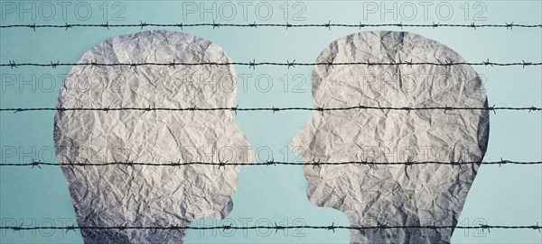 Two silhouettes of faces look at each other behind a barbed fence, refugee camp, prisoners