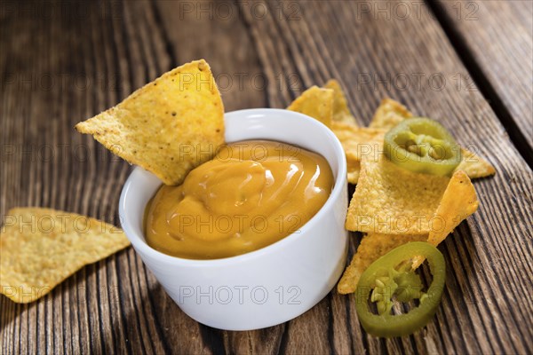 Portion of Nachos (with Cheese Dip) on an old wooden table