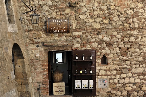 Montepulciano, Tuscany, Italy, Europe, Rustic wine cellar with a stone wall and wine bottles,