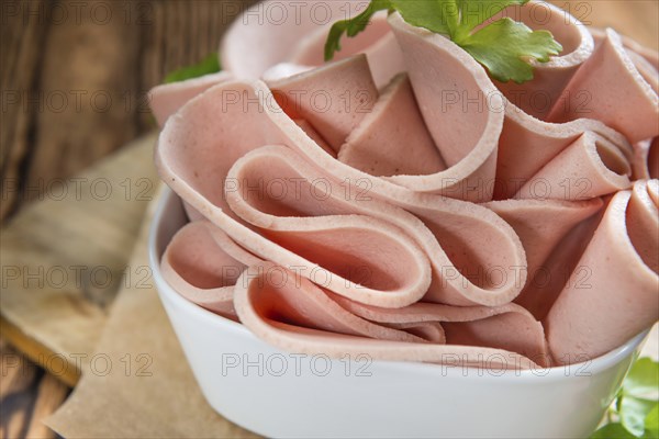 Portion of sliced Mortadella on wooden background (selective focus)