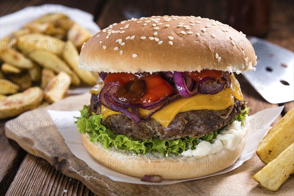 Big fresh made Burger on rustic wooden background (with French Fries)
