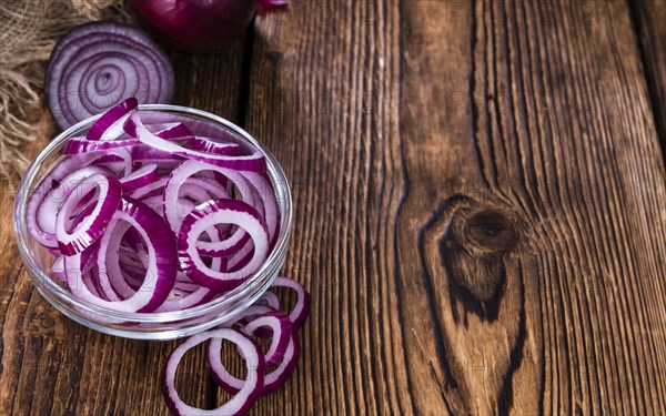 Fresh cutted Red Onion rings (close-up shot) on an old wooden table