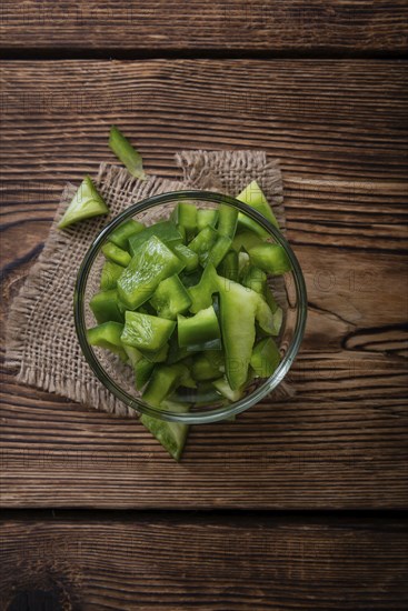 Portion of green Peppers (sliced, selective focus) on wooden background