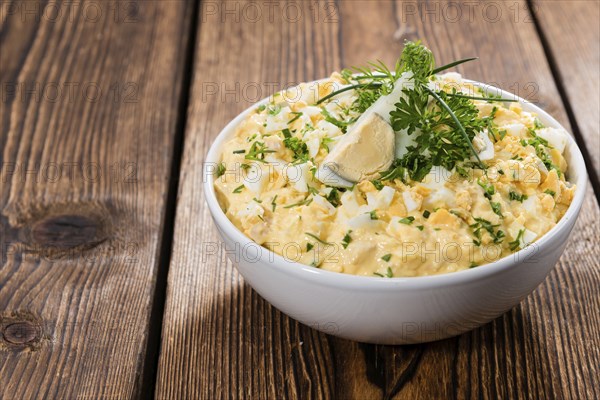 Portion of Egg Salad (fresh homemade with herbs) on wooden background