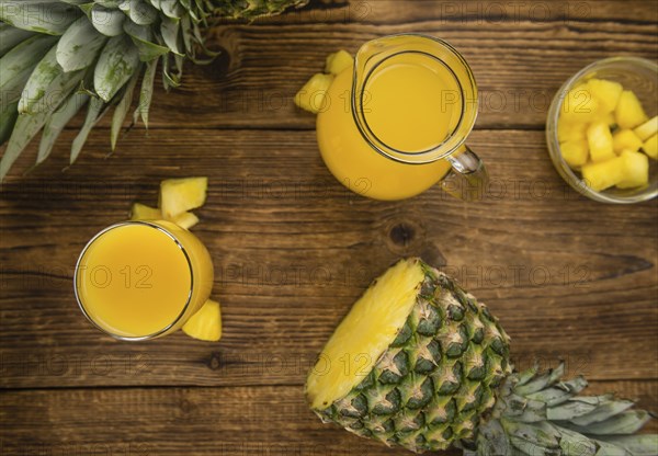 Pineapple Juice as high detailed close-up shot on a vintage wooden table, selective focus