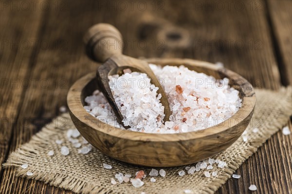 Salt (pink) on an old wooden table as detailed close-up shot (selective focus)