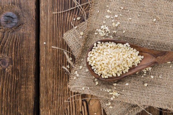 Portion of Minced Almonds (detailed close-up shot) on dark wooden background