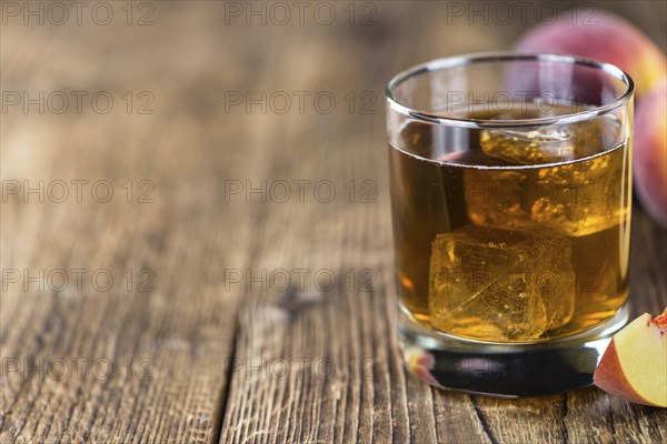 Fresh made peach ice tea (selective focus) on an old wooden table (close-up shot)