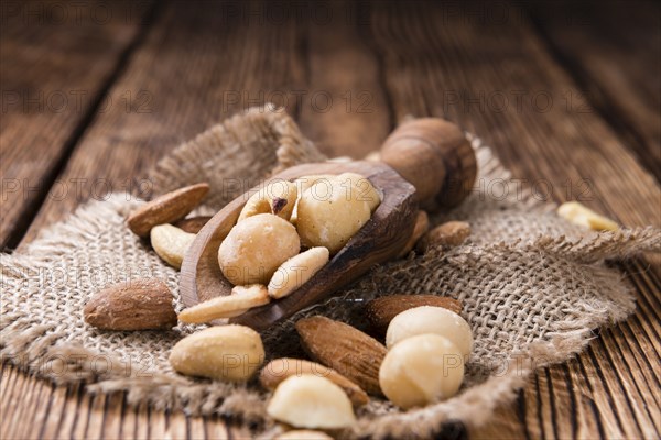 Portion of mixed nuts (roasted and salted) on an old wooden table (selective focus)