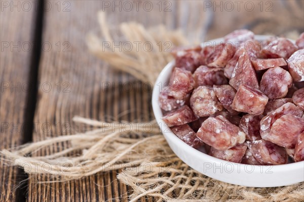 Portion of Mini-Salamis (detailed close-up shot) on wooden background