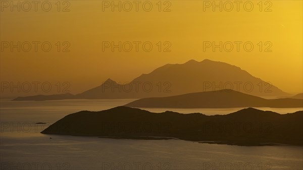 Golden sunset over the sea with silhouetted mountains in the background, Makri Island, Alimia