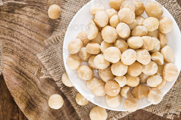 Portion of Macadamia nuts (roasted and salted) on wooden background