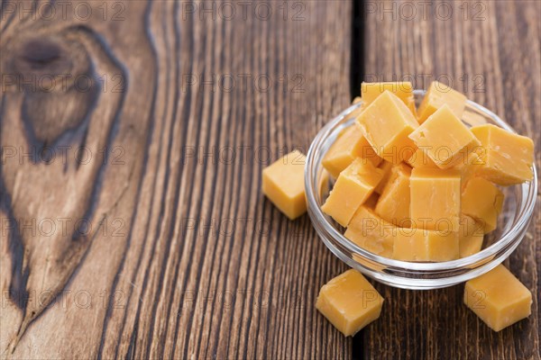Pieces of Cheddar (close-up shot) on an old wooden table