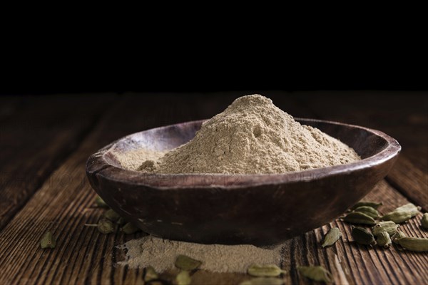 Heap of Cardamon Powder (close-up shot) on rustic wooden background