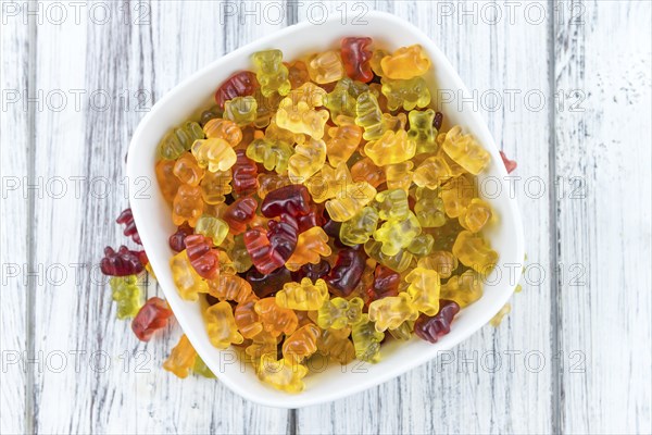 Bowl with Gummy Candy (selective focus) on wooden background