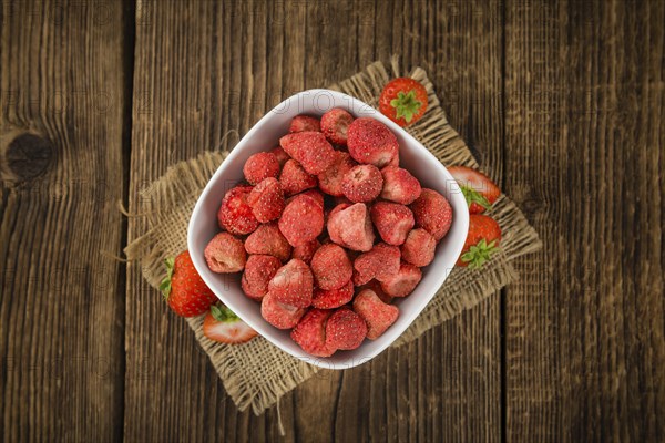 Strawberries (dried) as high detailed close-up shot on a vintage wooden table, selective focus