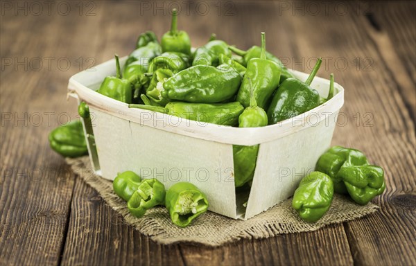 Raw Pimientos on rustic wooden background as close-up shot