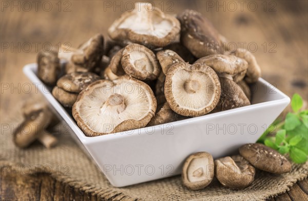 Raw Shiitake mushrooms as high detailed close-up shot on a vintage wooden table, selective focus