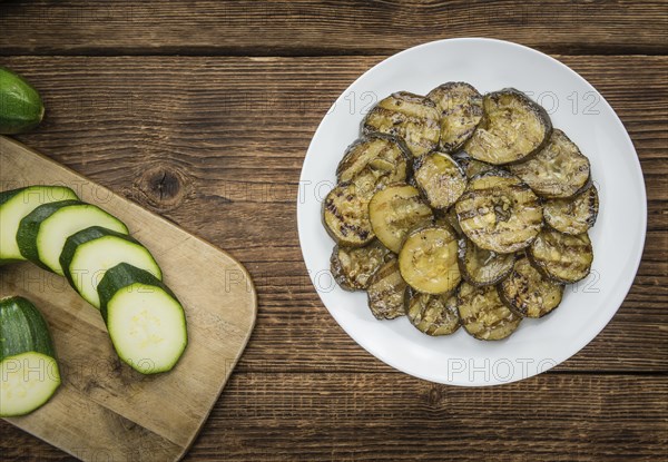 Zucchinis (grilled) as high detailed close-up shot on a vintage wooden table (selective focus)