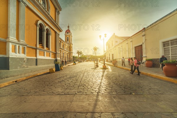 Urban view of people walking through the streets of Granada Cathedral at sunset. Granada, Nicaragua