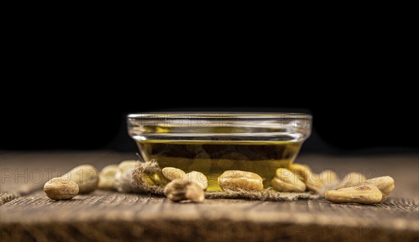 Fresh made Cashew Oil on an old wooden table (close-up shot, selective focus)