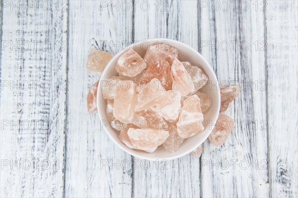 Wooden table with a portion of pink Salt (close-up shot, selective focus)