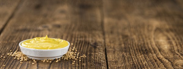 Mustard as high detailed close-up shot on a vintage wooden table (selective focus)