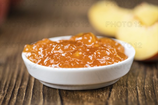 Peach Jam (selective focus) on an old wooden table (close-up shot)