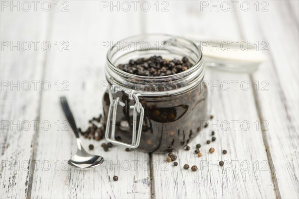 Black Peppercorns preserved on wooden background, selective focus, close-up shot