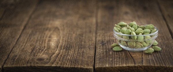 Wasabi coated Peanuts as high detailed close-up shot on a vintage wooden table (selective focus)