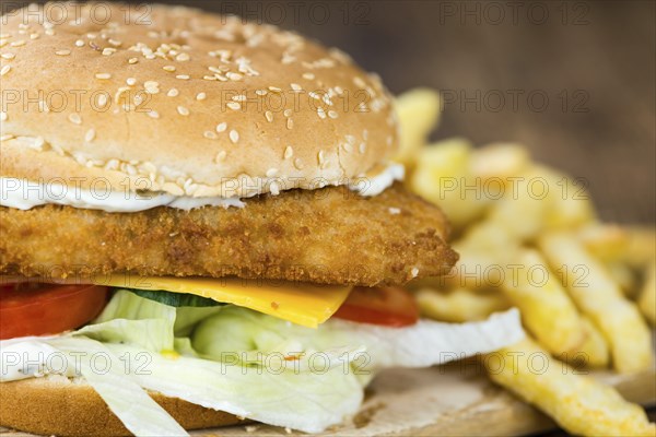 Wooden table with a fresh made Fish Burger (close-up shot, selective focus)