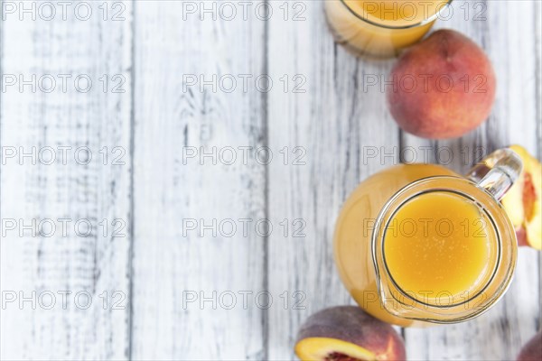 Portion of Peach juice (fresh made) on an old wooden table (close-up shot)
