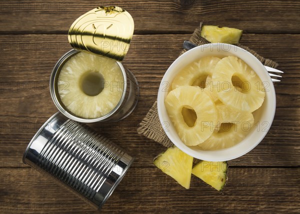 Preserved Pineapple Rings as high detailed close-up shot on a vintage wooden table, selective focus