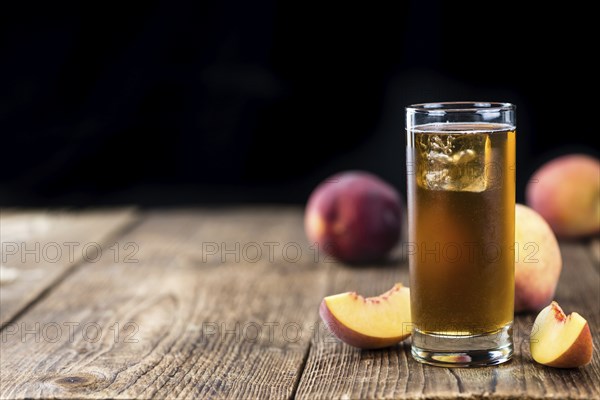 Old wooden table with fresh made tasty peach ice tea (selective focus)