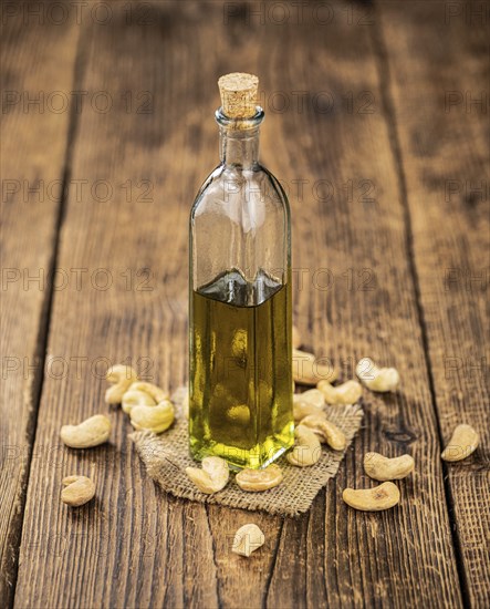 Fresh made Cashew Oil on an old wooden table (close-up shot, selective focus)