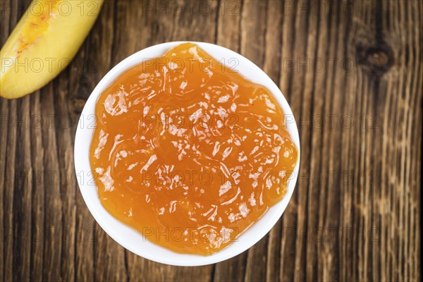 Wooden table with Peach Jam (selective focus, close-up shot)