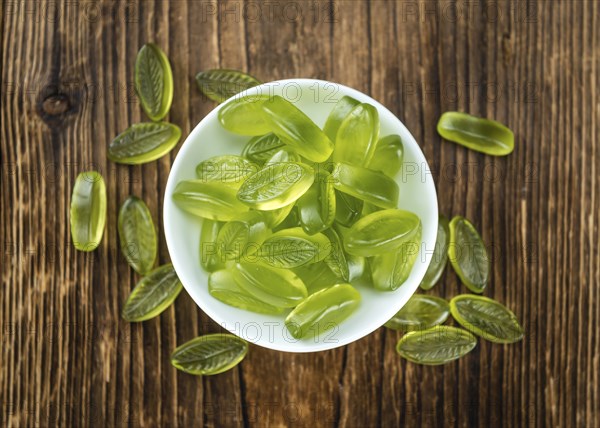 Heap of gummy candy with lime taste on wooden background (selective focus, close-up shot)