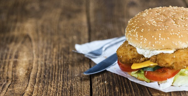 Wooden table with a fresh made Fish Burger (close-up shot, selective focus)
