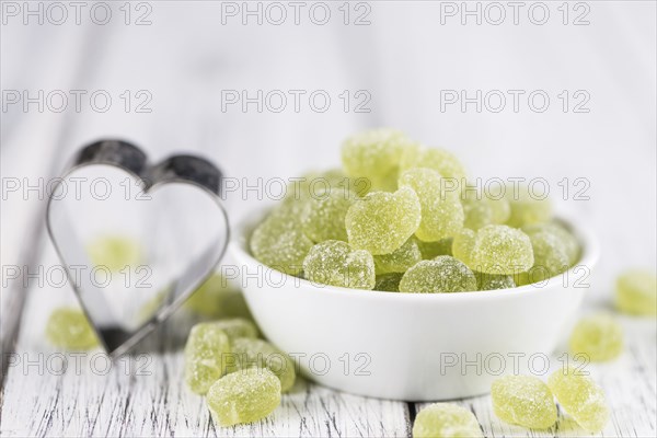 Sour gummy candy (apple taste) on an old wooden table (selective focus)