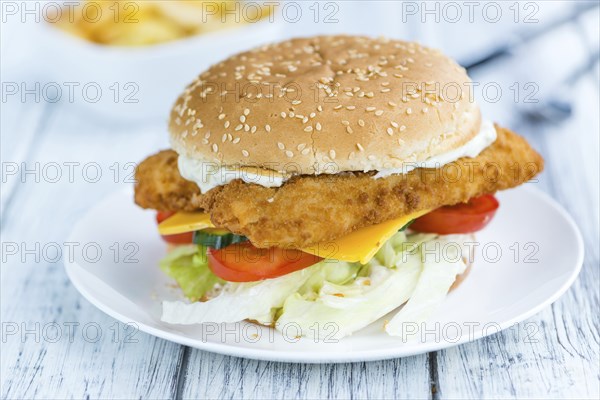 Fish Burger (selective focus, close-up shot) on wooden background