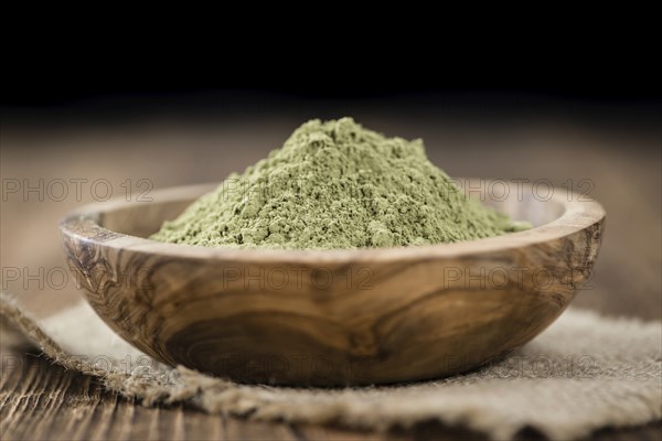 Portion of Stevia leaf powder (detailed close-up shot) on rustic wooden background