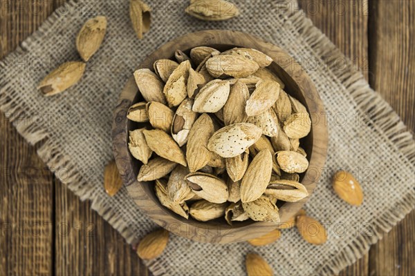 Almonds in shell (roasted and salted) on a vintage background (close-up shot)