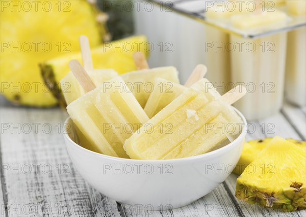 Fresh made Popsicles (Pineapple flavoured, selective focus) on a rustic background